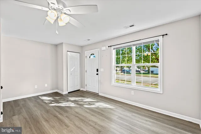 a view of an empty room with a window and wooden floor