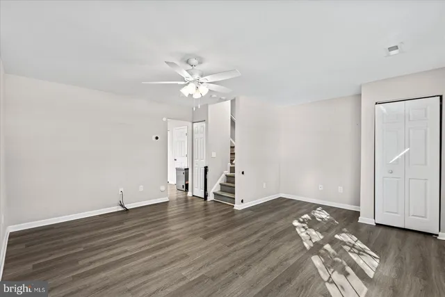 an empty room with wooden floor and ceiling fan