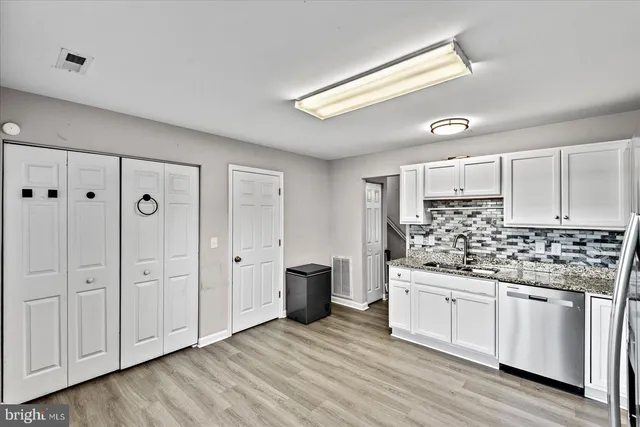 a kitchen with white cabinets and sink