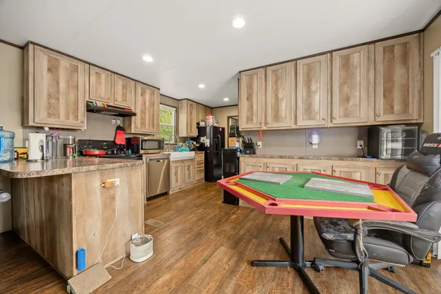 a kitchen with stainless steel appliances kitchen island granite countertop a table chairs and a refrigerator