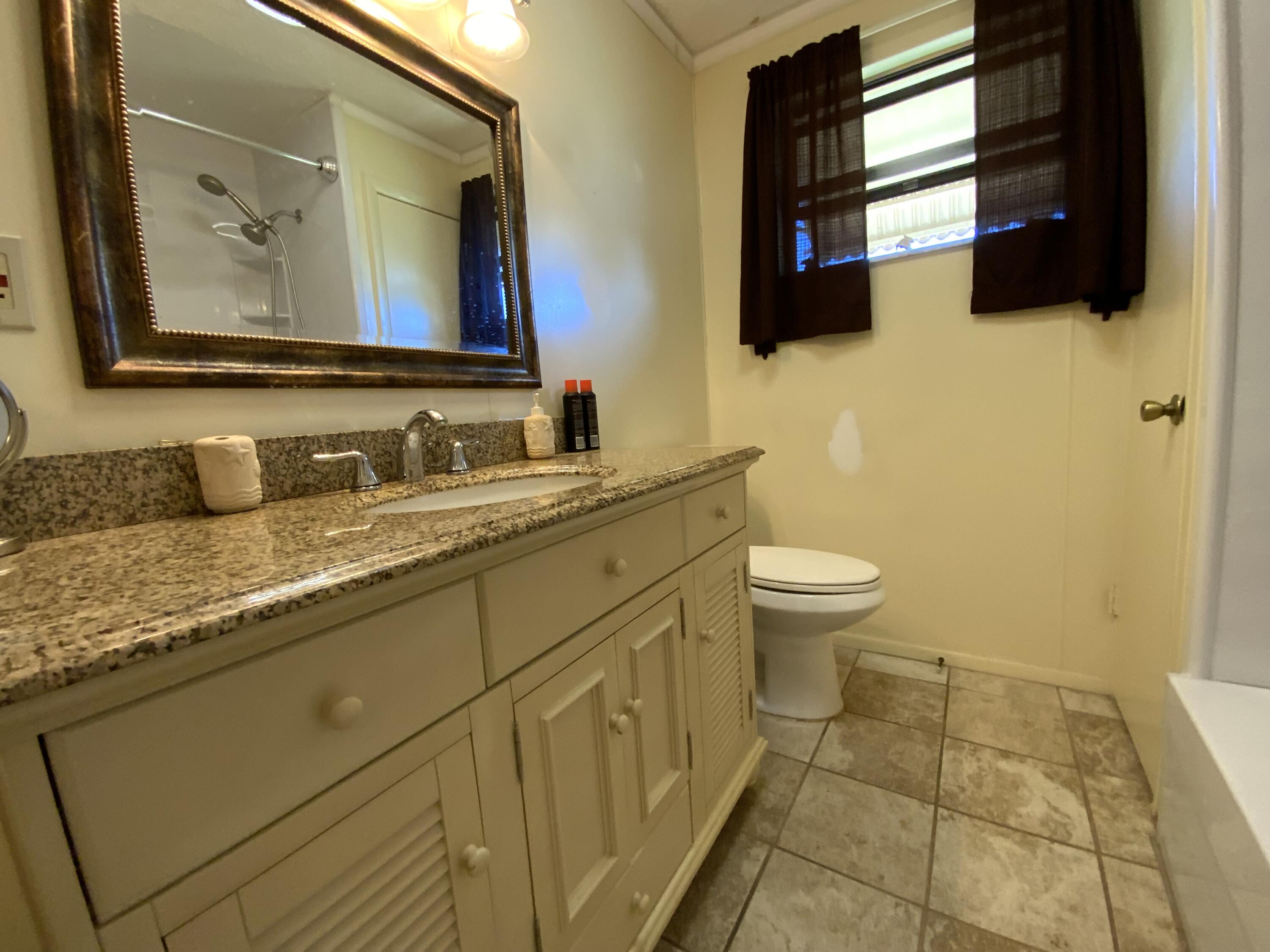 1095 Chobee Loop Okeechobee, FL 34974 - Photo 29 of 46 a bathroom with a granite countertop toilet sink and mirror