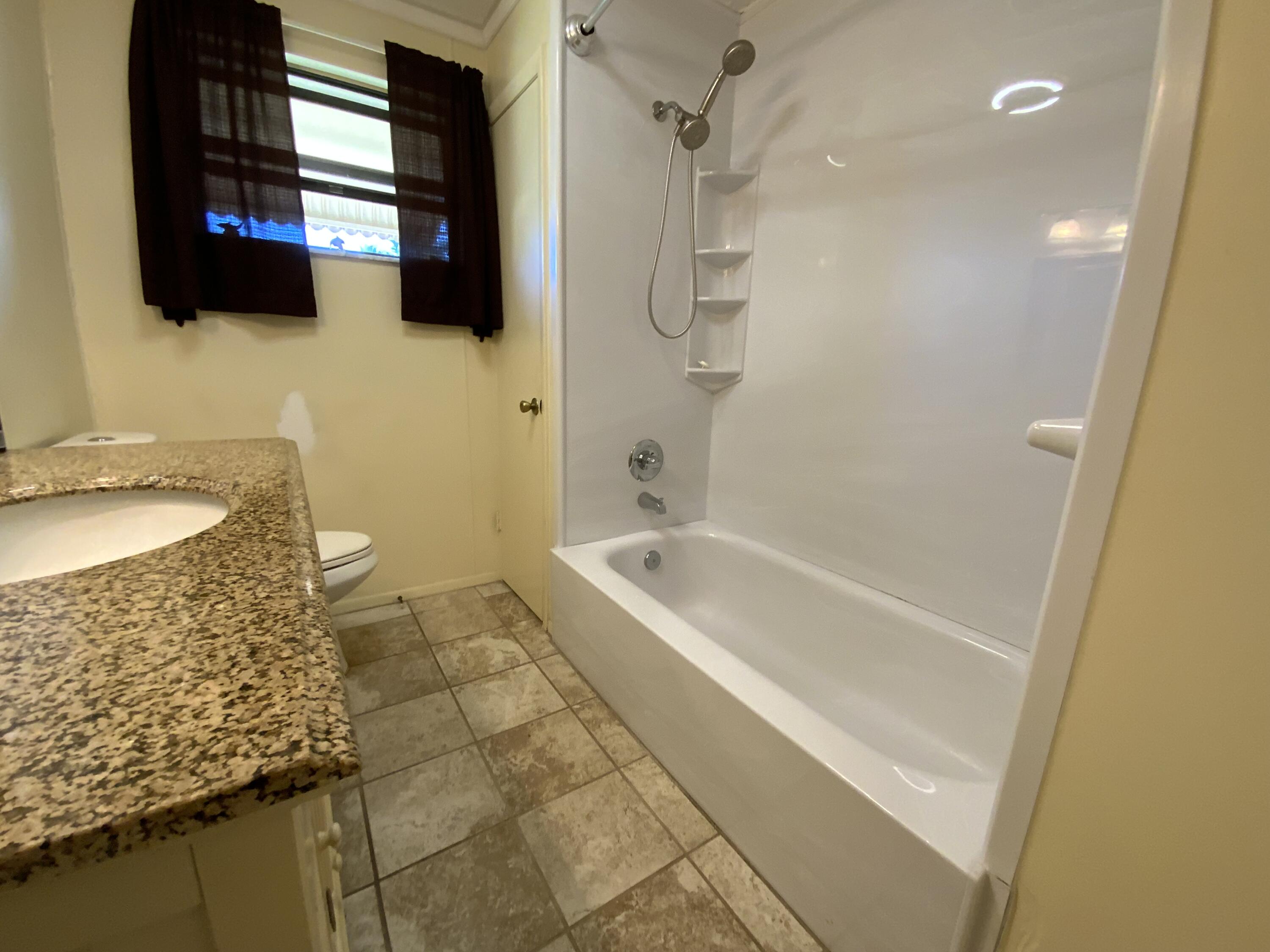 1095 Chobee Loop Okeechobee, FL 34974 - Photo 31 of 46 a bathroom with a granite countertop sink a mirror and bathtub