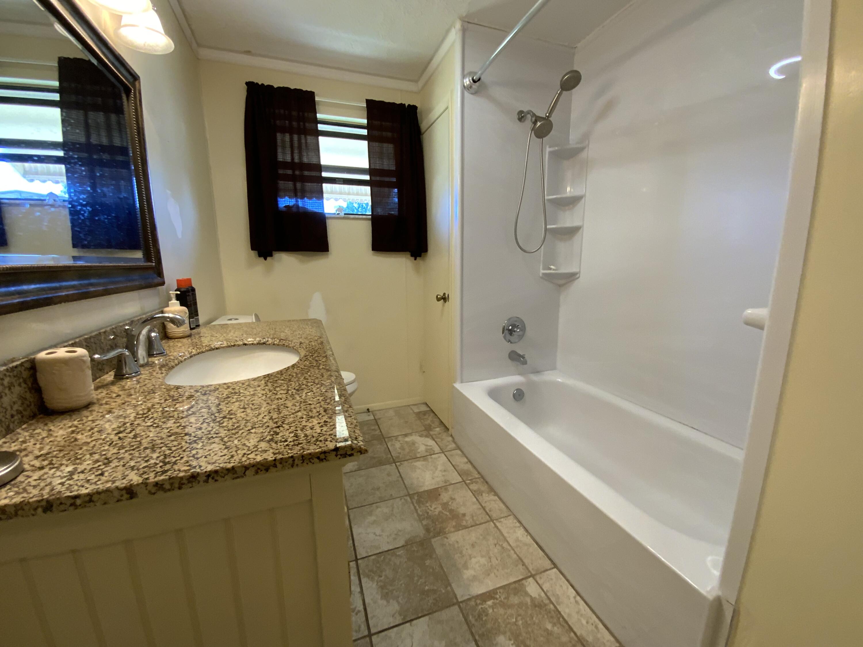 1095 Chobee Loop Okeechobee, FL 34974 - Photo 32 of 46 a bathroom with a granite countertop sink and a mirror