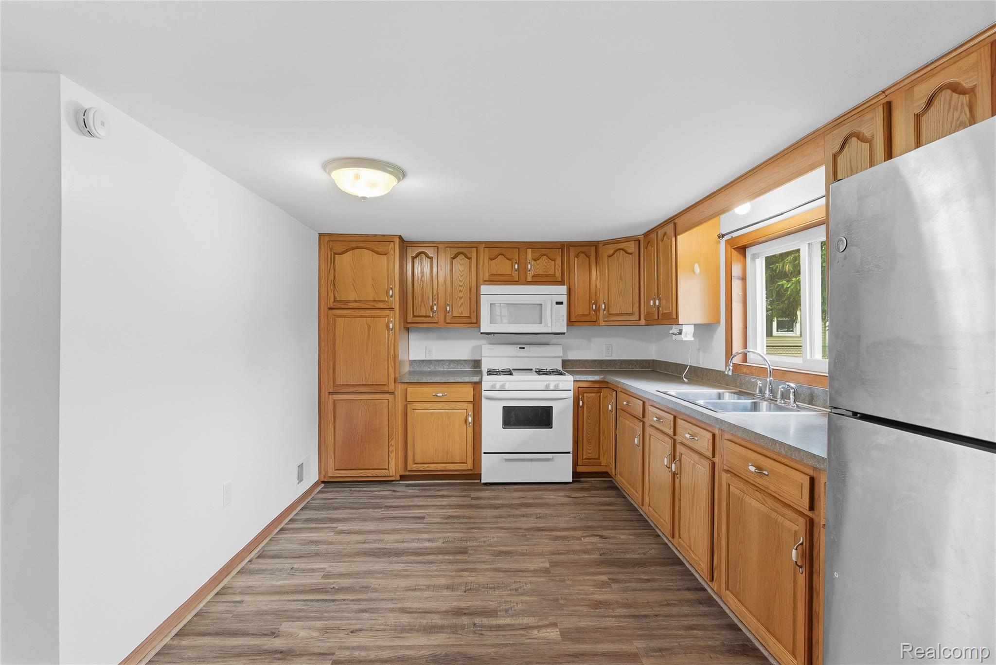 1843 Curtis Road Birch Run, MI 48415 - Photo 6 of 25 Kitchen featuring wood-finish flooring, a full suite of appliances, and ample cabinetry
