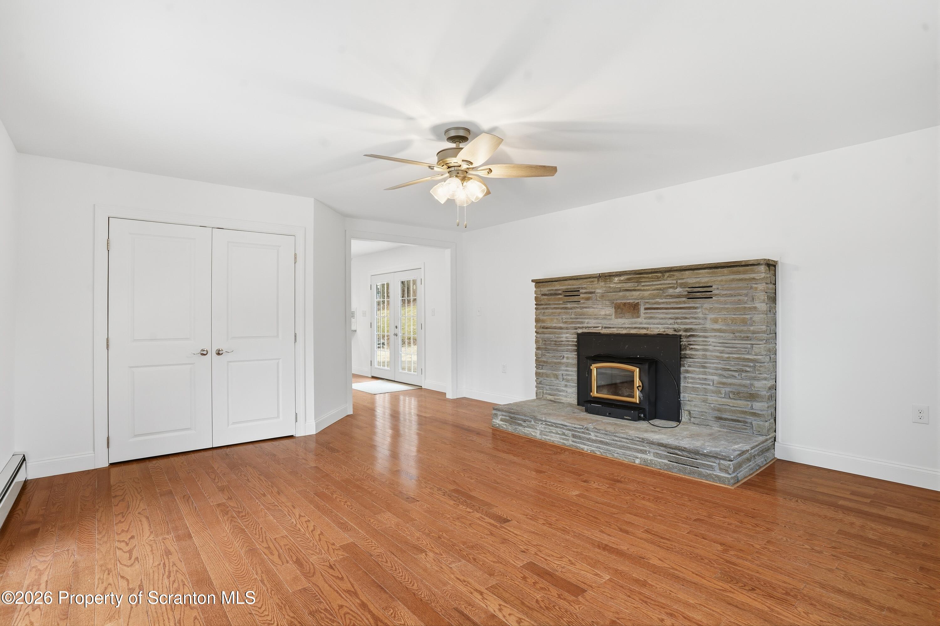 16204 Highway 407 Factoryville, PA 18419 - Photo 22 of 74 a view of a livingroom with a fireplace a chandelier fan and wooden floor