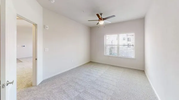 an empty room with windows and fan
