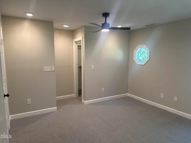 an empty room with ceiling fan and window