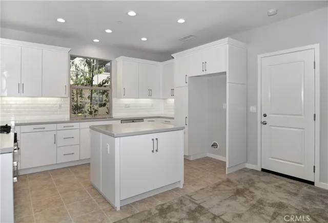 a kitchen with white cabinets and refrigerator