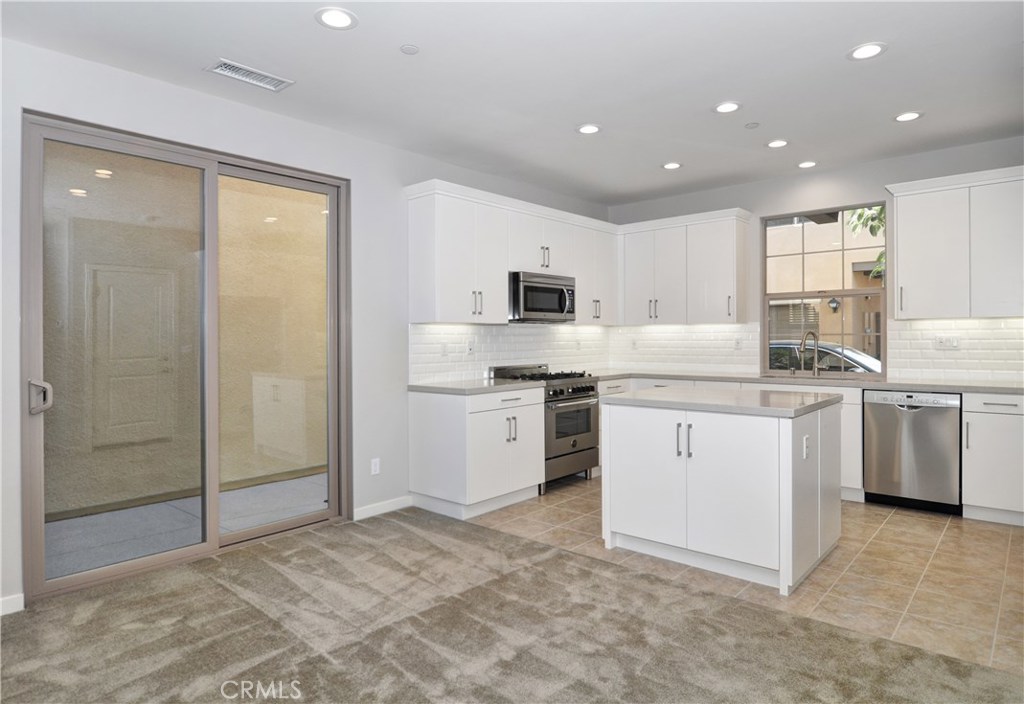 123 Quiet Grove Irvine, CA 92618 - Photo 5 of 16 a kitchen with white cabinets and white appliances