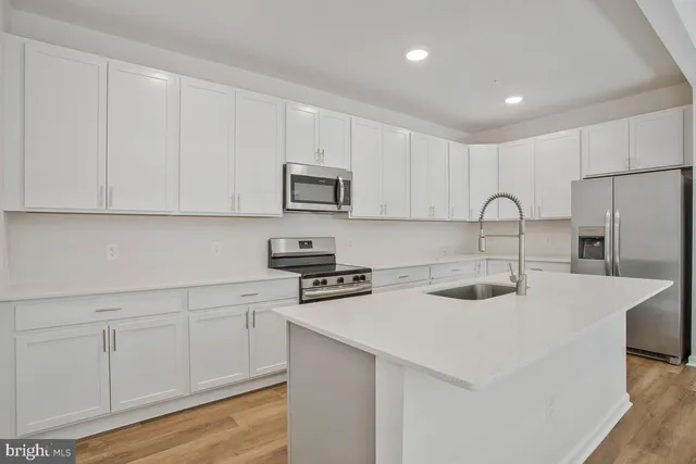 a kitchen with a sink dishwasher and wooden floor