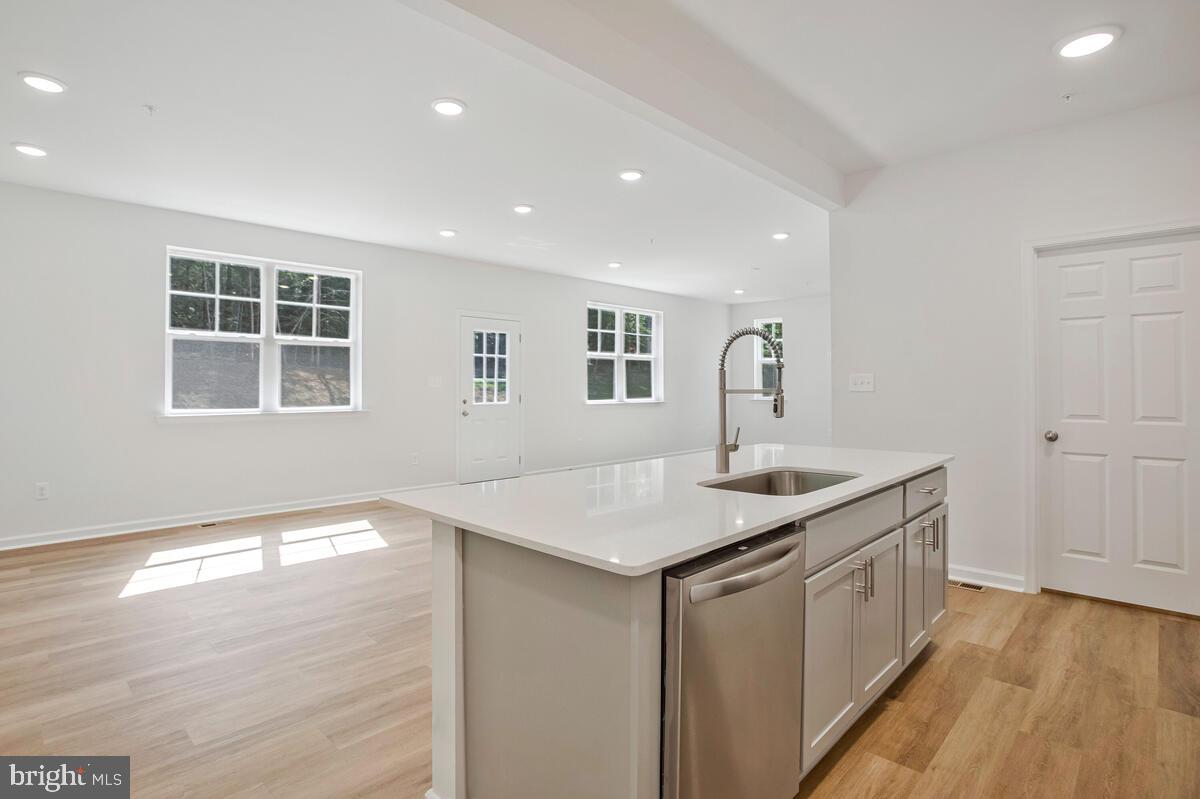 900 Walnut Avenue North Beach, MD 20714 - Photo 15 of 82 a kitchen with a sink dishwasher and white cabinets with wooden floor
