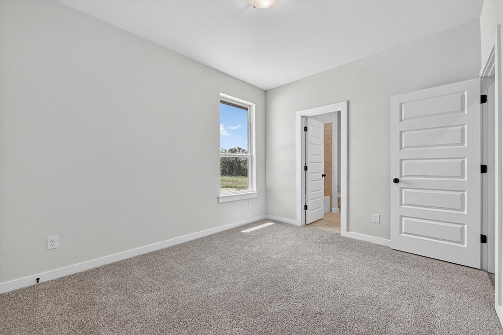 409 Mcalpine Springtown, TX 76082 - Photo 27 of 38 Carpeted room with light gray wall paint, white baseboards, and a single window
