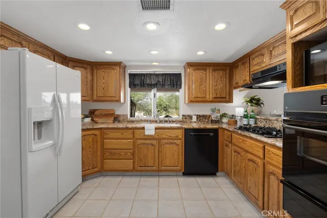 a kitchen with stainless steel appliances granite countertop a refrigerator and a stove top oven