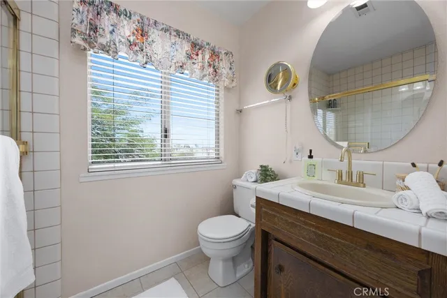 a bathroom with a granite countertop bathtub sink vanity mirror and toilet