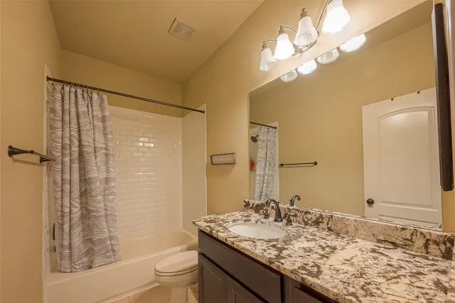 a bathroom with a granite countertop sink toilet and shower