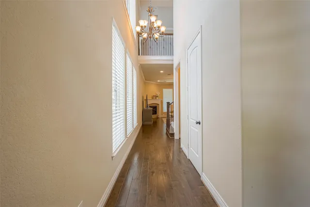 a view of a hallway with wooden floor and a chandelier