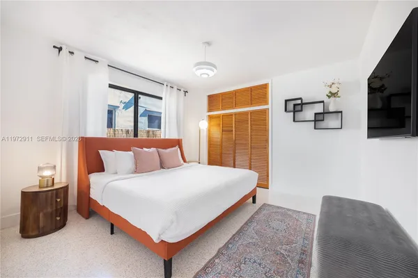 a bedroom with a bed flat screen tv and window