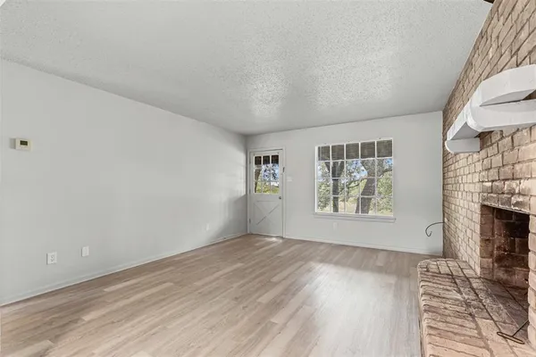 a view of empty room with wooden floor and fireplace