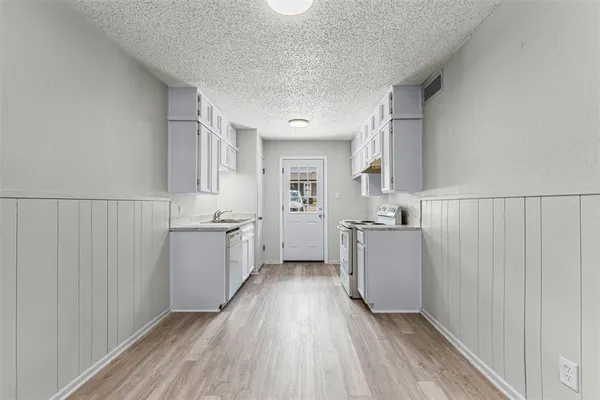 a kitchen with cabinets and wooden floor