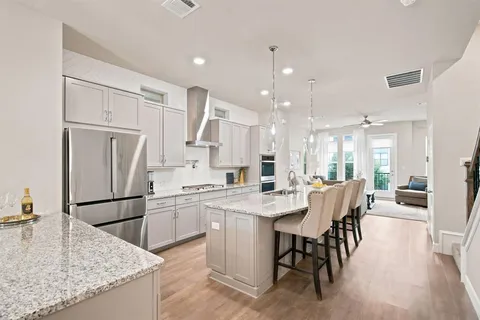 a kitchen with stainless steel appliances granite countertop dining table chairs and wooden floors