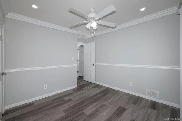 an empty room with wooden floor and ceiling fan