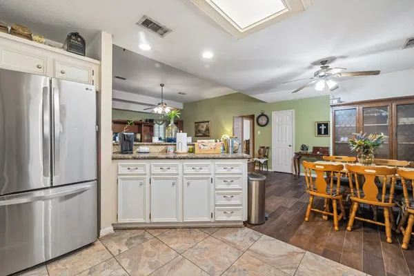 a kitchen with stainless steel appliances a dining table chairs and refrigerator