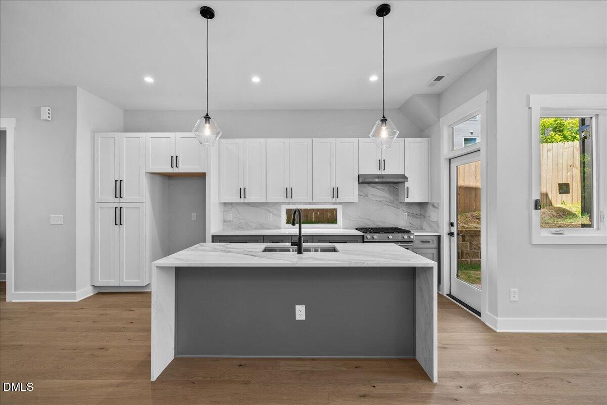 541 Bragg Street Raleigh, NC 27601 - Photo 5 of 44 a kitchen with stainless steel appliances granite countertop a sink a stove a refrigerator and island with wooden floor