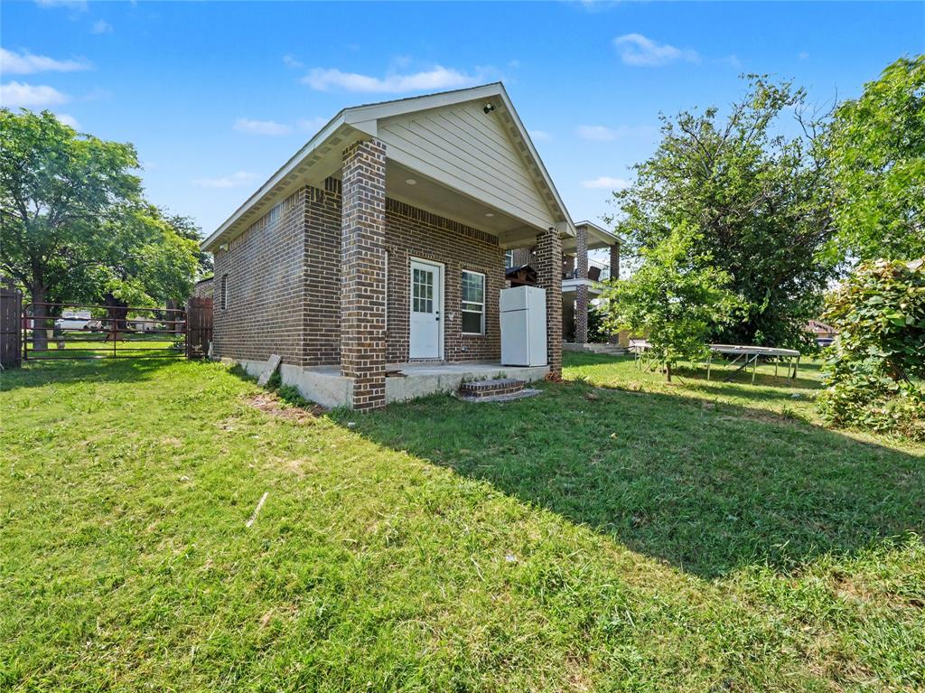 6701 Nauert Road Forest Hill, TX 76140 - Photo 33 of 40 Brick exterior with white paneled door, covered patio, concrete slab foundation, and fenced perimeter