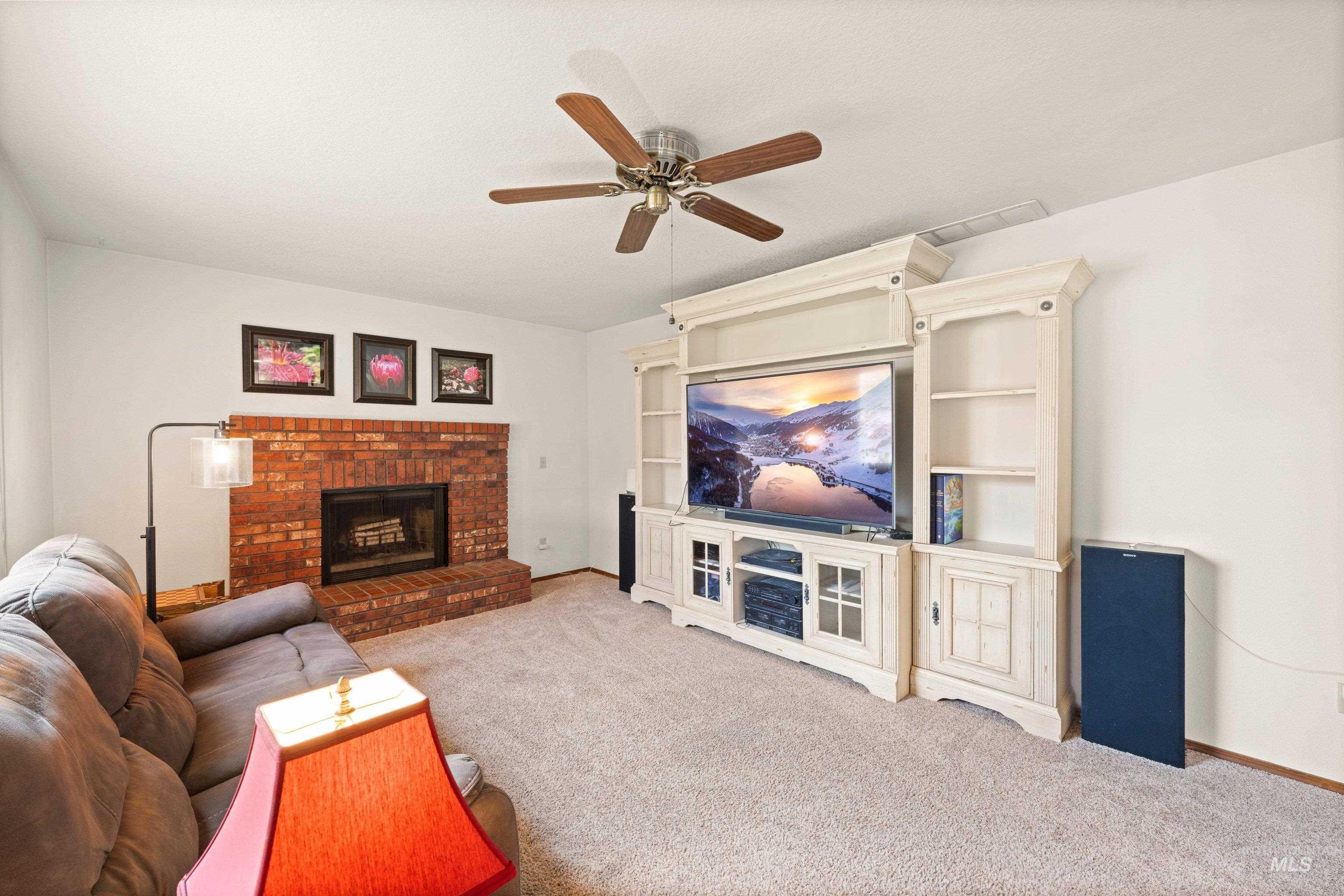 1921 Incline Way Meridian, ID 83646 - Photo 18 of 50 Living area featuring a brick fireplace, built-in entertainment center, ceiling fan, and light-toned carpet