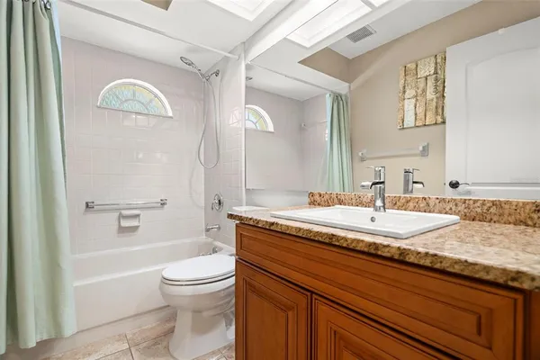 a bedroom with a bed a dresser and a chandelier