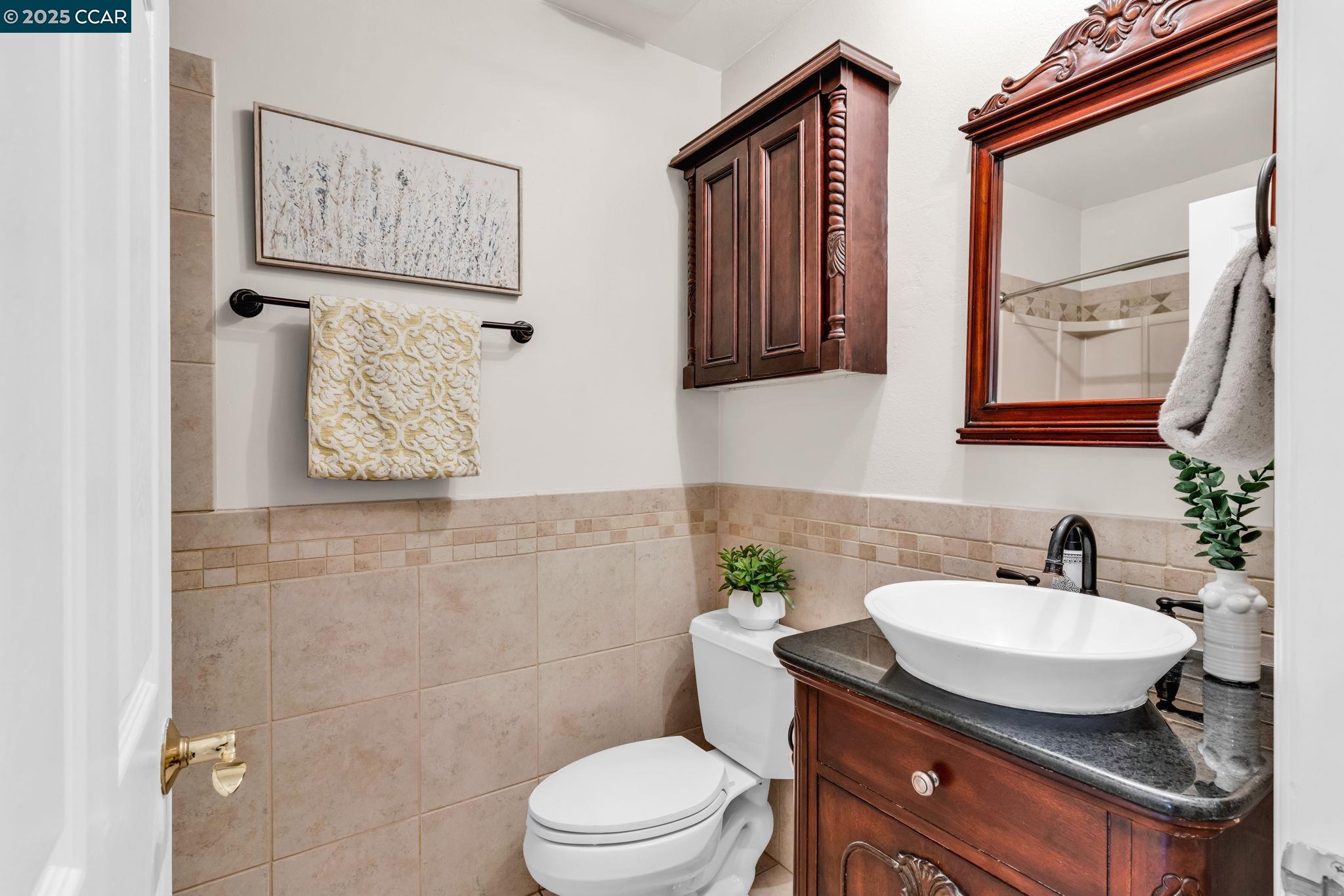 4380 St Charles Place Concord, CA 94521 - Photo 27 of 54 a bathroom with a granite countertop sink a mirror and a toilet