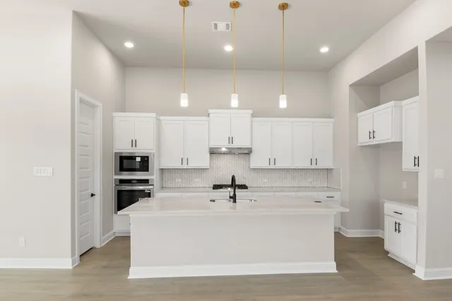 a large white kitchen with a kitchen island sink stove and white cabinets