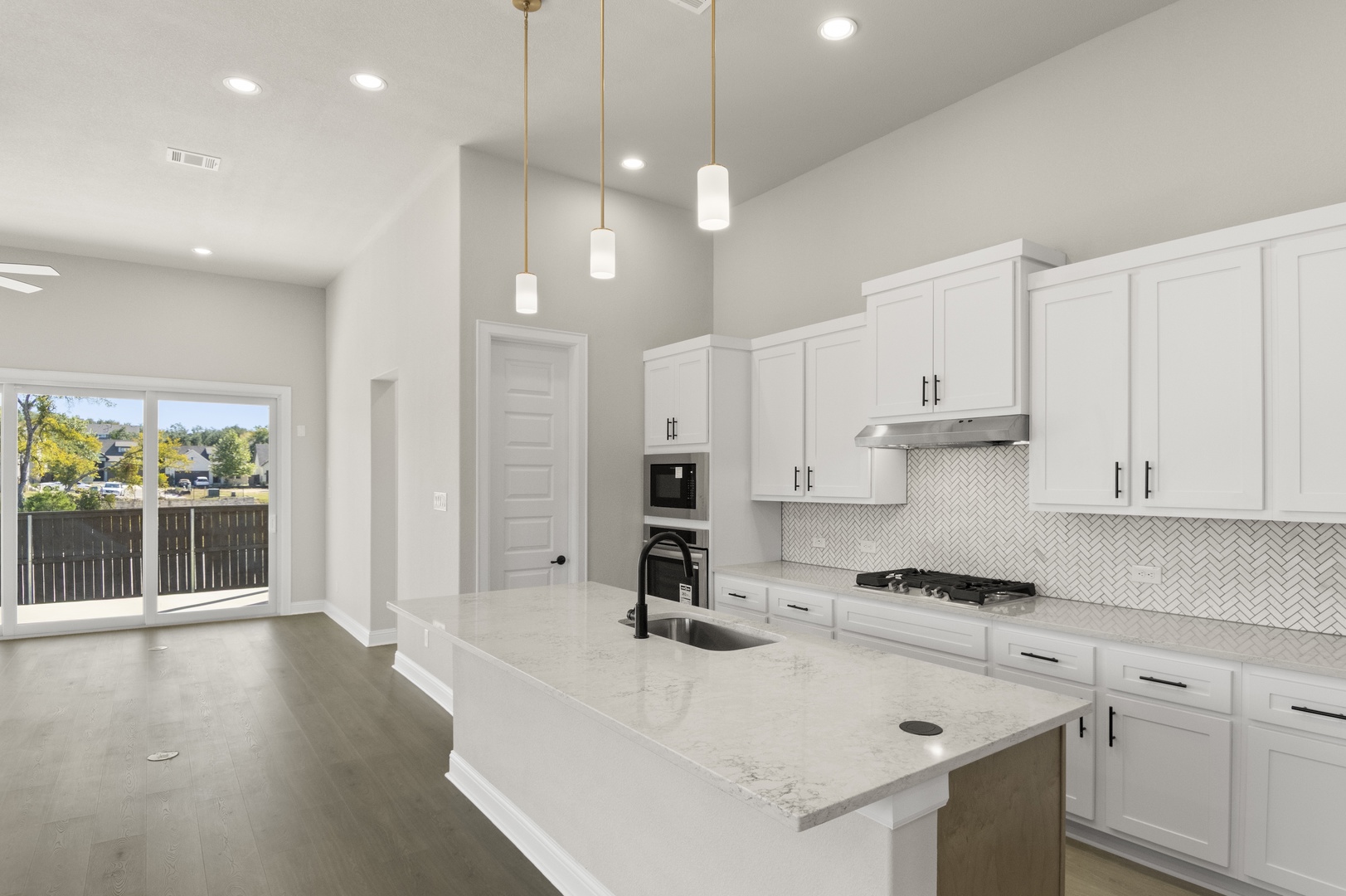 601 C-Bar Ranch Trail, Unit 59 Cedar Park, TX 78613 - Photo 16 of 34 Kitchen featuring backsplash, an island with sink, light stone counters, white cabinetry, and hanging light fixtures