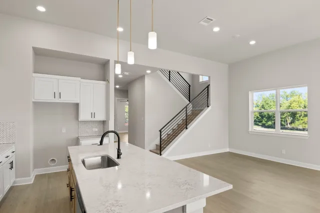 a kitchen with stainless steel appliances granite countertop a sink a oven a dining table and chairs with wooden floor