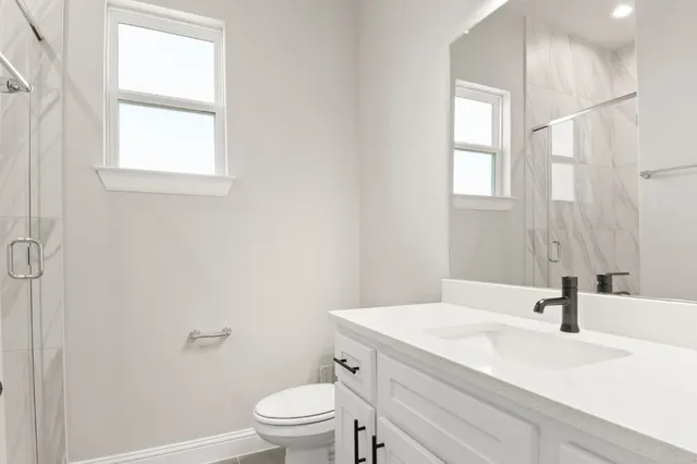 a bathroom with a granite countertop sink a toilet and a window