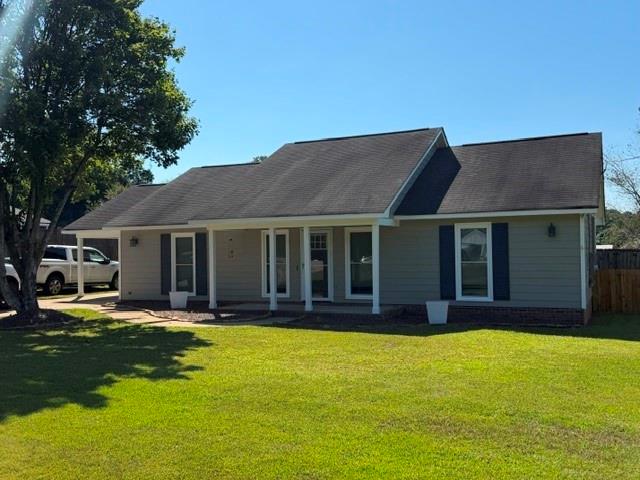 Single-story residence featuring siding exterior, a covered front entry with columns, black shingle roofing, and a grass lawn