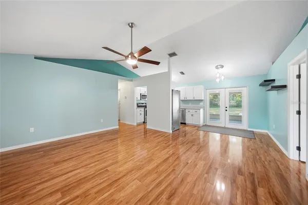 a view of an empty room with wooden floor and a window