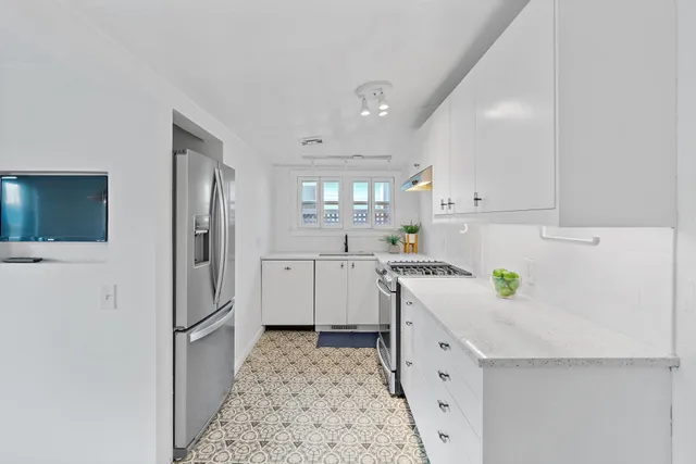 a kitchen with a refrigerator a sink and wooden floor