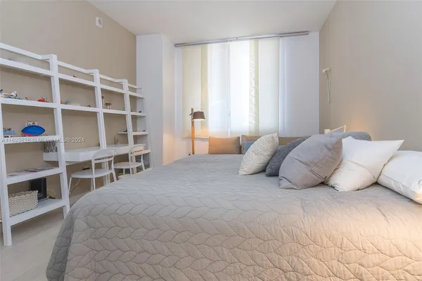 a large white bed sitting in a bedroom next to a window