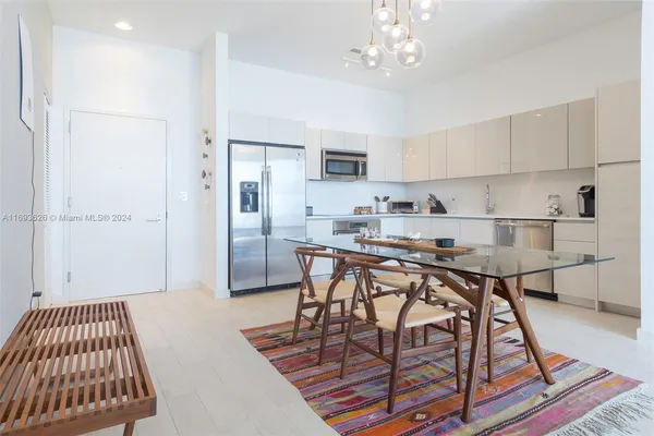 a kitchen with stainless steel appliances granite countertop a sink dishwasher a refrigerator with white cabinets and wooden floor