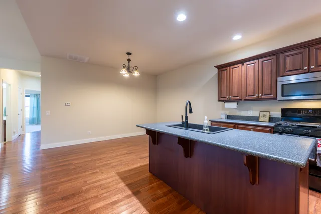a kitchen with stainless steel appliances granite countertop a sink a stove and a wooden floors