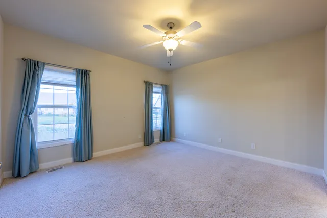 an empty room with windows and chandelier fan