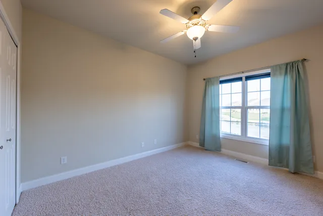 a view of a big room with windows and chandelier fan