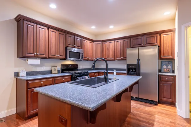 a kitchen with stainless steel appliances granite countertop a sink stove microwave and refrigerator