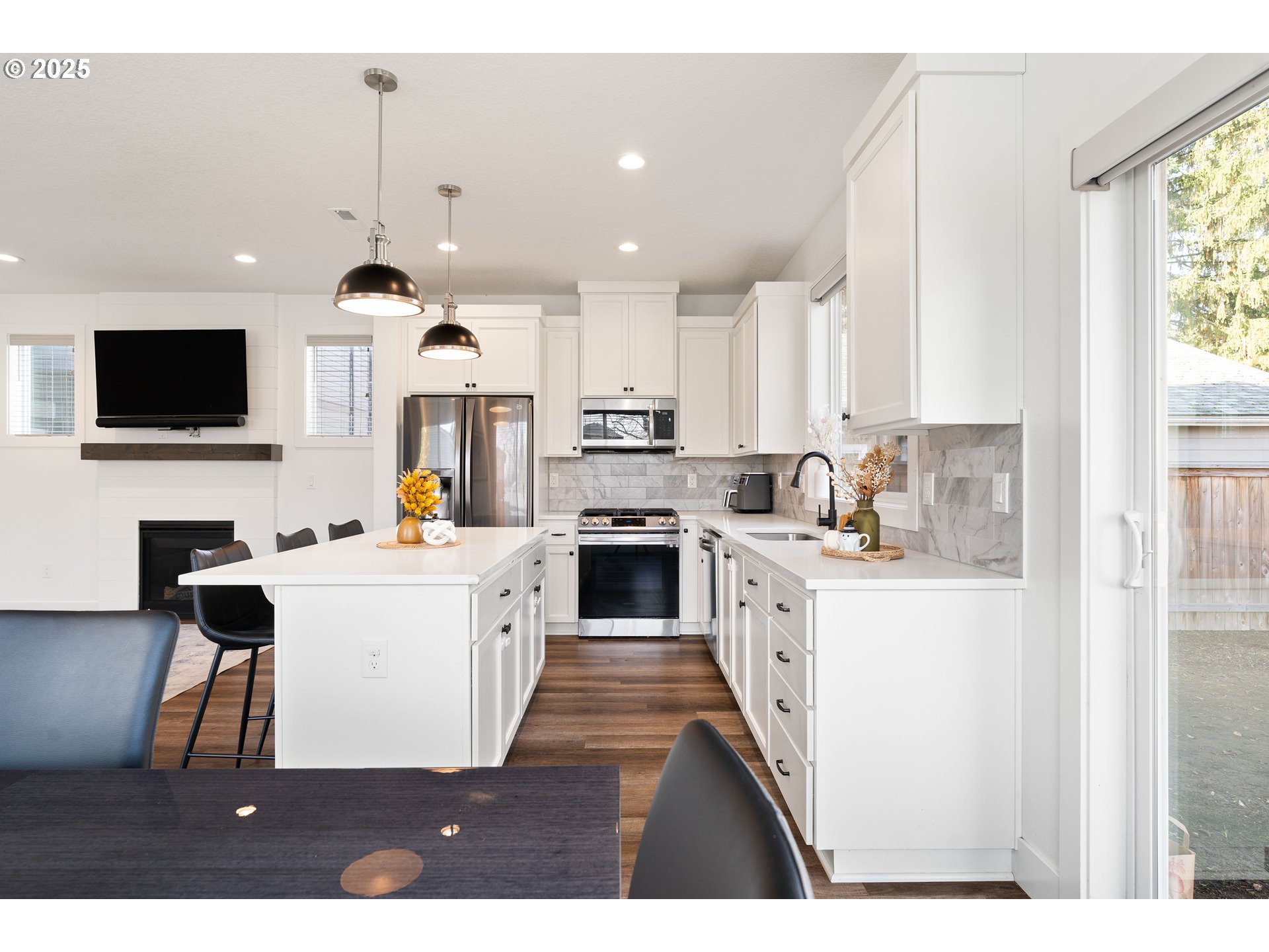 6421 Southeast Cooper Street Portland, OR 97206 - Photo 16 of 44 a large white kitchen with granite countertop a stove top oven a sink a dining table and chairs with wooden floor