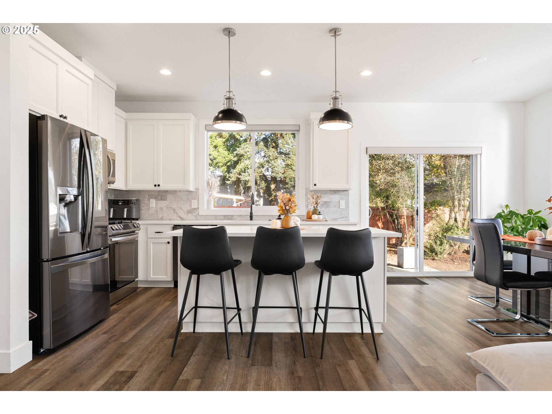 6421 Southeast Cooper Street Portland, OR 97206 - Photo 19 of 44 a kitchen with stainless steel appliances kitchen island granite countertop a refrigerator a stove a dining table and chairs with wooden floor