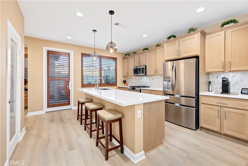 39320 Brunello Way Temecula, CA 92591 - Photo 6 of 52 a kitchen with stainless steel appliances granite countertop a refrigerator a sink dishwasher a stove and white cabinets with wooden floor