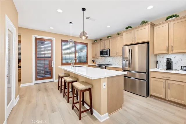 a kitchen with stainless steel appliances granite countertop a refrigerator a sink dishwasher a stove and white cabinets with wooden floor