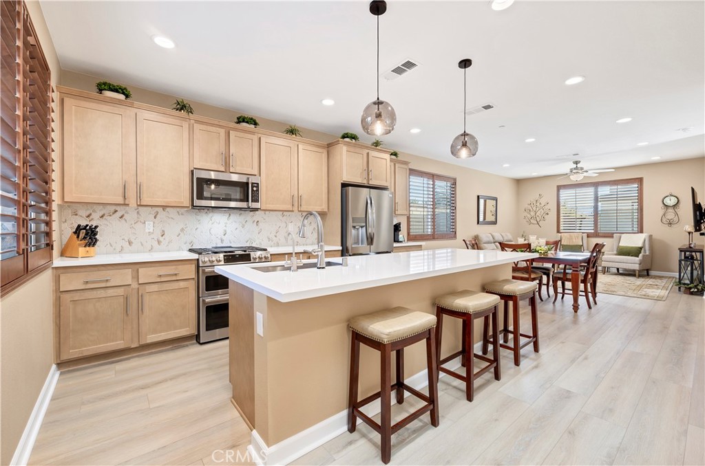 39320 Brunello Way Temecula, CA 92591 - Photo 9 of 52 a kitchen with stainless steel appliances kitchen island a table chairs sink and cabinets