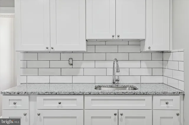 a kitchen with granite countertop white cabinets and a stove
